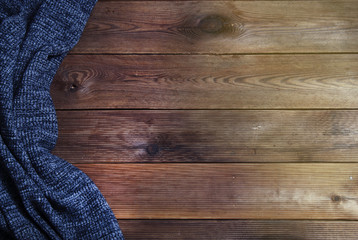 Warm Knitted textured dark gray blanket on a wooden background. Top view, space for text. Autumn and fall background.