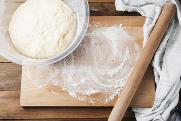 Whole wheat pizza or pie dough, shaped into ball on floured wooden background. Cooking at home.