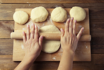 Female Hands Making Dough for baking pie, or pizza. Homemade Preparing Food. Top view. Rustic background.