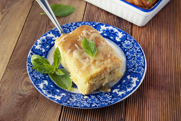Piece of homemade pie with cheese. Blue vintage plate. Rustic wooden board. Healthy food.