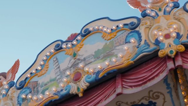 Beautiful illuminated merry-go-round details while rounding at Christmas fair in slow motion. Vintage colorful carousel with angel on the top