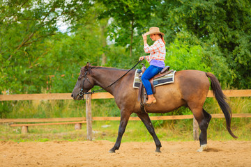 Cowgirl doing horse riding on countryside meadow