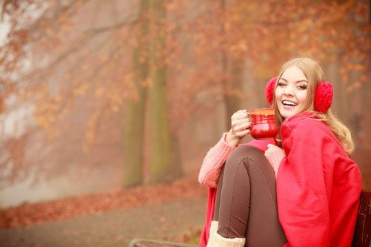 Girl in autumn park enjoying hot drink
