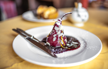 Pear in wine. Traditional dessert pear stewed in red wine on yellow background.