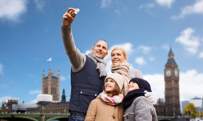 family, travel and tourism concept - happy mother, father, daughter and son taking selfie by camera...