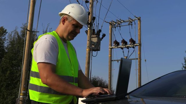 Electrician using portable computer and take transformer technical inspection