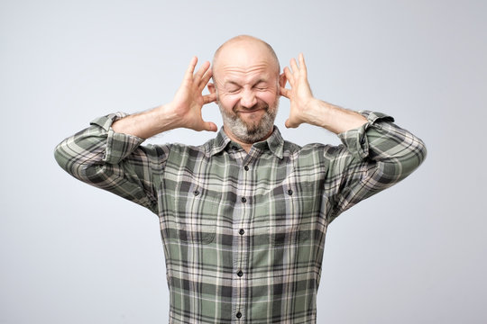 Annoyed Mature Man Plugging Ears With Fingers