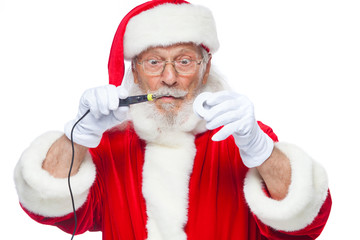 Christmas. Santa Claus in white gloves holding a soldering iron with a solder. Electronics,...