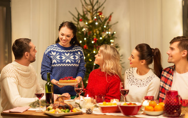 holidays and celebration concept - happy friends having christmas dinner at home