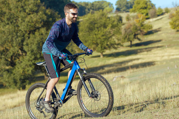 Obraz premium A cyclist rides the hills, Beautiful portrait of a guy on a blue bicycle 