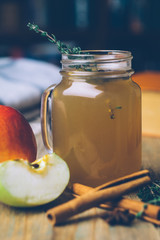 Apple cider (mulled cider) with cinnamon sticks and fresh apples on wooden background. Autumn drinks. Winter mood.