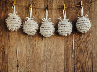 Christmas decorations white textile snowballs on the wooden background. Christmas decorations, toys for the Christmas tree hanging on clothespins. Copy Space