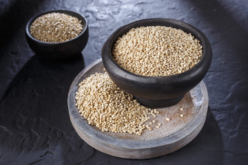 Quinoa grains with spoon and bowl on black background