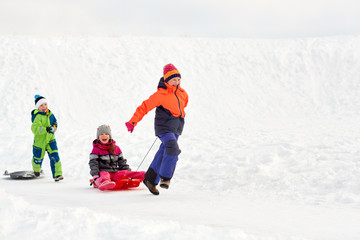 Fototapeta na wymiar childhood, leisure and season concept - group of happy little kids in winter clothes with sled having fun outdoors