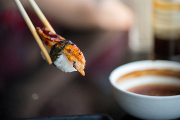 Close up chopsticks hold on sushi freshwater eel grilled. Japanese food for healthy. unagi sushi, premium sushi menu. image for background,wallpaper, copy space and menu list.
