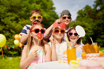 holidays, childhood and celebration concept - happy kids with party props on birthday in summer...