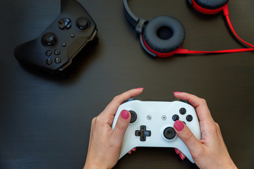 Woman hand holding white joystick gamepad, game console on black background. Computer gaming competition videogame control confrontation concept