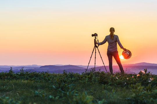Woman is photographing sunset. Enjoying spending time with camera in nature