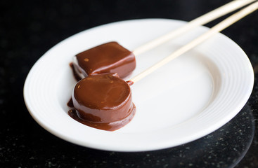 Girl holds a marshmallow into Chocolate fondue fountain. Sweets and dessert decoration. Food culture from switzerland.