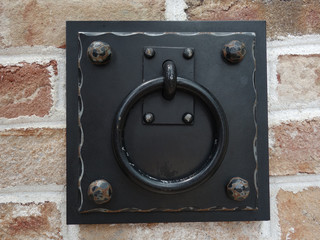 Door knocker on a beige brick wall      