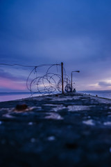 Militärische Mauer an einem düsteren sonnenuntergang mit maschendrahtzaun am meer