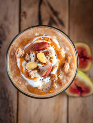 Close-up of oats and chia seeds pudding with figs, on wooden background, top view