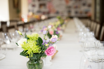 Served for a banquet table. Wine glasses with napkins, glasses and plates. flower vase