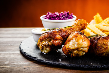 Grilled drumsticks with french fries and vegetables on wooden background
