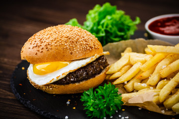 Tasty burger with chips served on cutting board