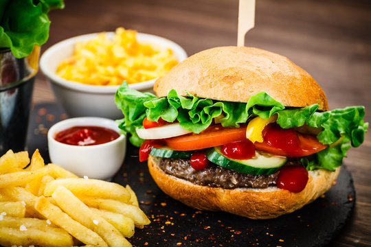 Tasty hamburgers with french fries served on fashionable black stone plate
