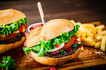 Tasty hamburgers with french fries served on fashionable black stone plate