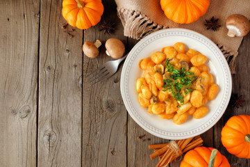 Gnocchi with a pumpkin, mushroom cream sauce. Autumn meal. Top view table scene on a rustic wood background with copy space. - obrazy, fototapety, plakaty