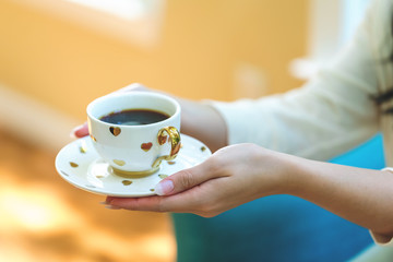 Young woman holding a cup of coffee in a chair in her home