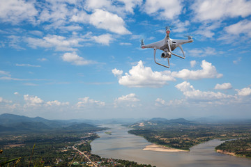 Fototapeta na wymiar UAV drone copter flying with digital camera.Drone with high resolution digital camera. Flying camera take a photo and video.The drone with professional camera takes pictures of the river and mountains