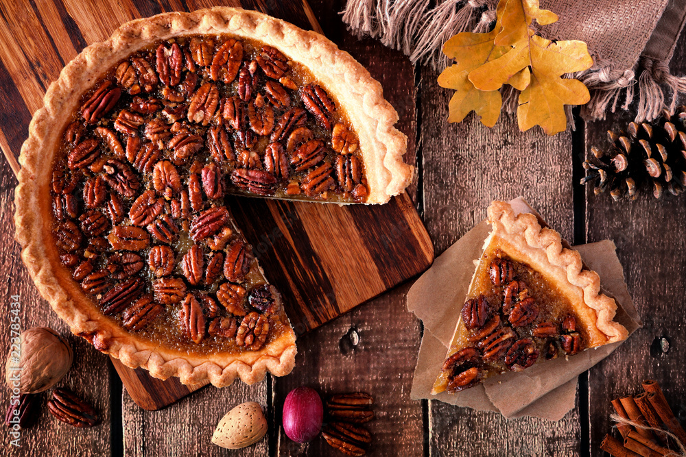 Poster autumn pecan pie, overhead table scene with cut slice on a rustic wood background