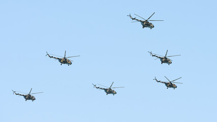 Military helicopters maneuvers in the blue sky. Group combat helicopters in flight during a military demonstration