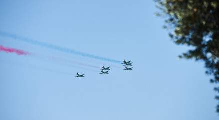 Modern military jet fighter airplanes flying in blue sky. Fighter jets fly together with colorful smoke