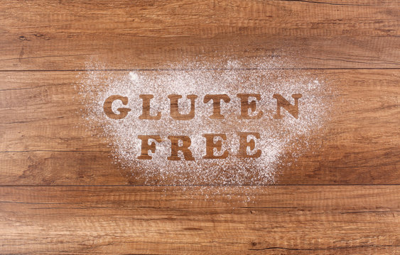 Gluten free written in flour on brown table