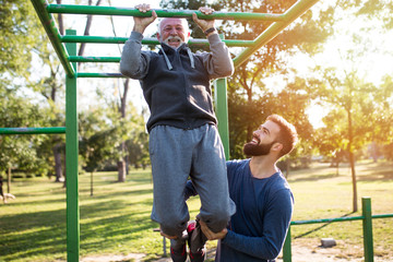 Happy good looking father and son exercising together in park.