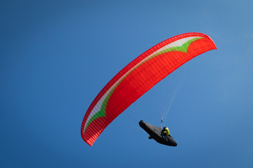 Close up, Guy flying on the clearly blue sky with a red paraglider,extreme activity