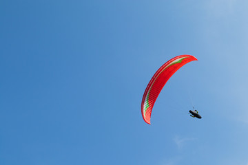 Red paraglider isolated on a clear blue sky
