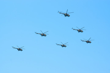 Fototapeta na wymiar Military helicopters maneuvers in the blue sky. Group combat helicopters in flight during a military demonstration