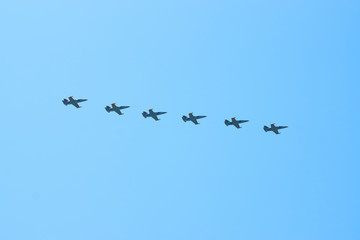 Obraz premium Modern military jet fighter airplanes flying in blue sky. Fighter jets fly together with colorful smoke