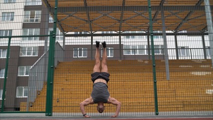 boy delightedly standing on his hands. On a white background. The athlete presses on his hands. The athlete stands on his hands and squeezes. The athlete stands on his hands