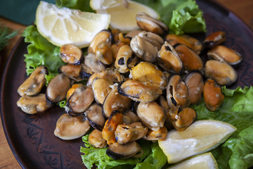 Closeup of green mussels and lemon in selective focus, top view of gourmet mussels