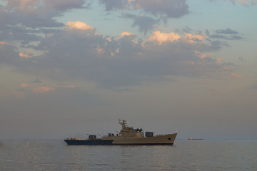 Military Battleships in a sea bay at sunset time. Modern warship sailing in still water. Coast Guard Ships guarding ocean