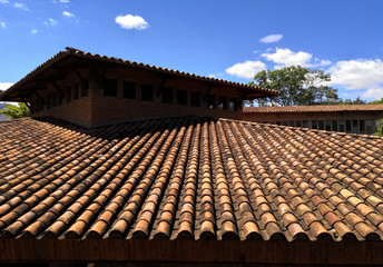 Obraz premium Roof with clay tiles. Day with blue and sunny sky. Traditional architecture details with bricks and tiles.
