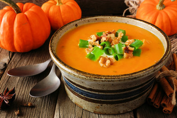Creamy pumpkin soup. Autumn food concept. Close up scene in a rustic bowl against wood.