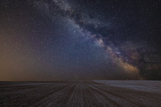 Vibrant Milky Way composite image over landscape of cultivated field