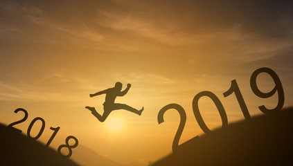 brave man successful concept,silhouette man jumping over the sun between gap of the mountain from 2018 to 2019 new year , it feel like a winner, success, finish,reach a goal of live, jobs,